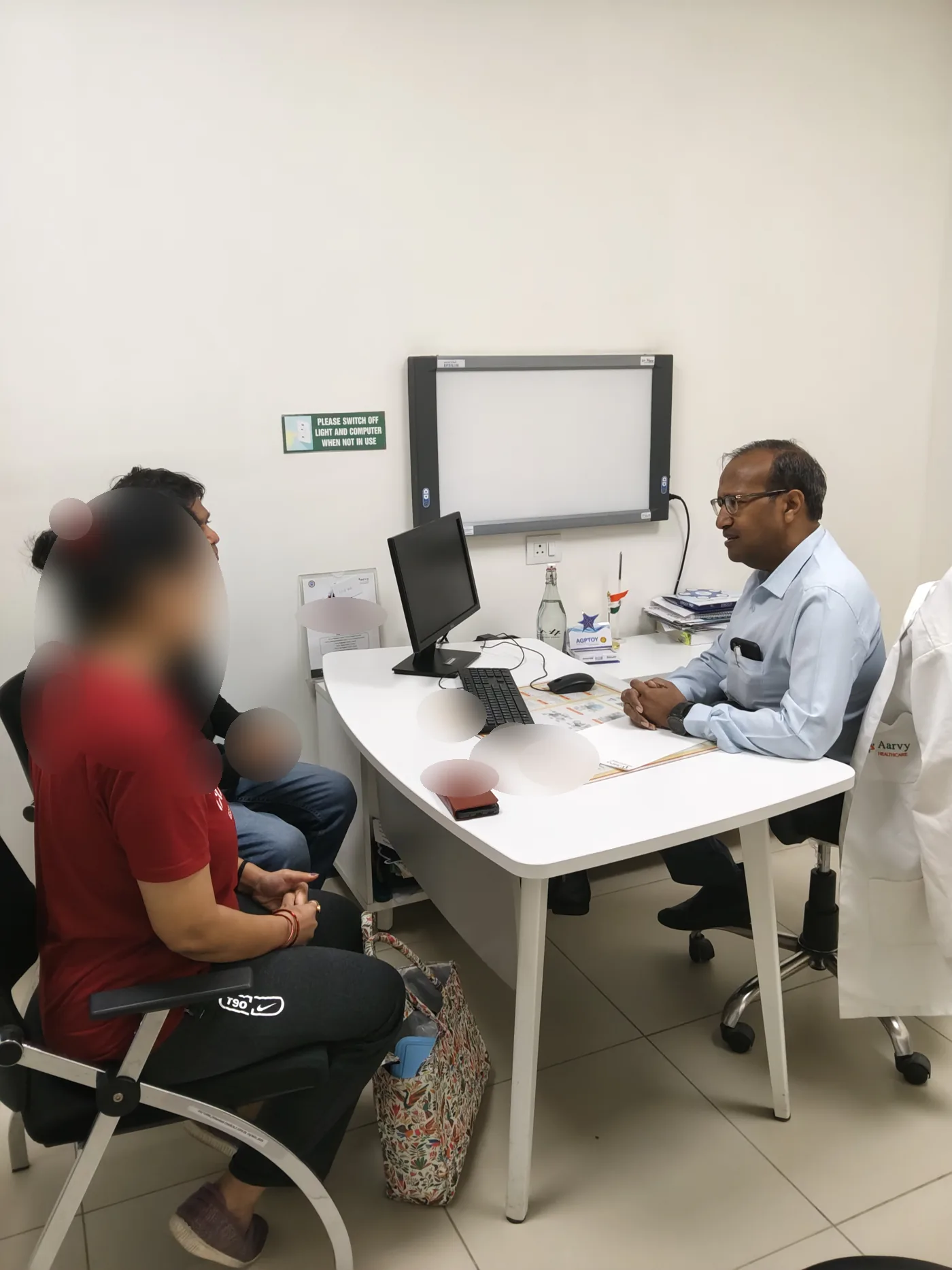 Dr. Deepak Kumar in an outpatient consultation. Patient faces are blurred.